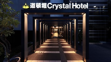 A pathway leading to a hotel entrance with illuminated signage.