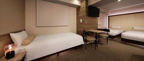 A hotel room with a bed, a desk, a chair, a TV, and a wall-mounted light fixture.