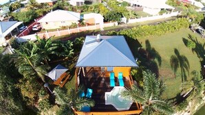 Un quartier résidentiel avec une maison dotée d’un toit bleu, d’une piscine et d’une terrasse avec des chaises bleues.