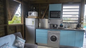 Une cuisine compacte équipée d’un lave-linge, d’un four à micro-ondes et d’un petit coin repas avec une table et des chaises.
