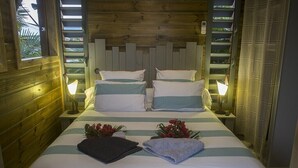 Un lit double avec une literie à rayures, deux tables de chevet avec des lampes et une tête de lit en bois.
