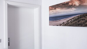 Een kamer met een witte deur en een schilderij van een strand.