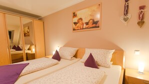 Habitación de hotel con dos camas, un armario, una mesita de noche y un cuadro en la pared.