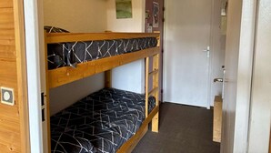 Habitación con literas, una puerta y un estante pequeño.