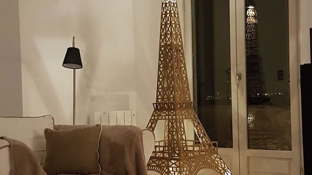 Ein Wohnzimmer mit einer Couch, einem Glastisch und einem dekorativen Modell des Eiffelturms.