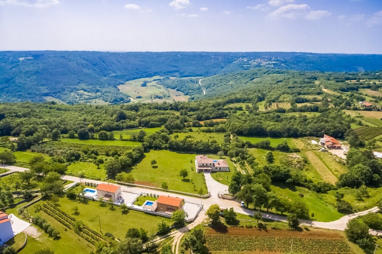 An aerial view of a rural property with fields, a swimming pool, and a large building.