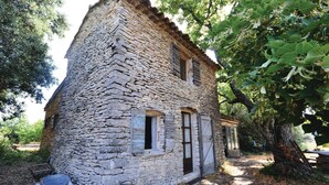 A stone house with a sloped roof, a wooden door, and a window. - 1 bedroom beautiful home in Saignon (Saignon)