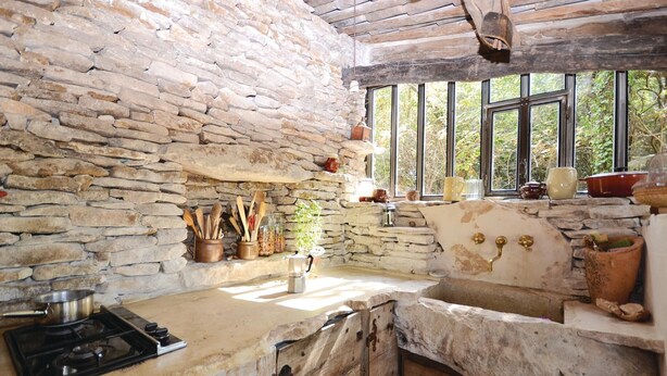 A rustic kitchen with stone walls, a wooden countertop, and a window with a view of greenery. - 1 bedroom beautiful home in Saignon (Saignon)