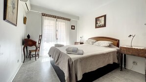 Ein Schlafzimmer mit einem Bett, einem Schreibtisch, einem Stuhl und einem Fenster mit Vorhängen.