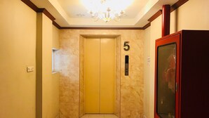 A hallway with a marble floor, a chandelier, and a door marked with the number 5.