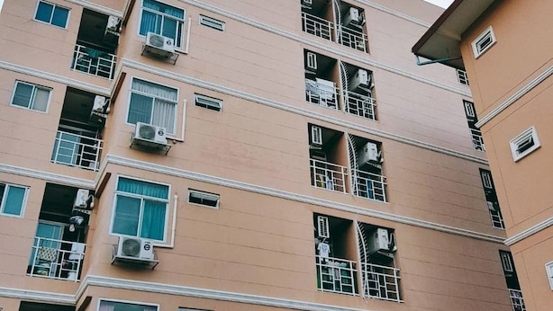 A multi-story building with balconies, air conditioning units, and a sign indicating it is a hotel.
