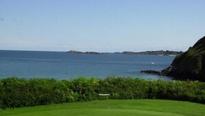 Un parcours de golf offrant une vue sur la mer et sur la terre au loin.