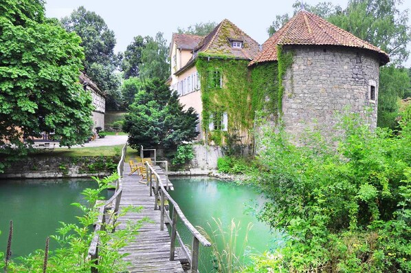 A stone tower with ivy, a wooden bridge, and a river.