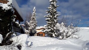 A snow-covered landscape with a wooden cabin and a house in the background. - 02, 2-room app. 40sqm, terrace, cooking facilities, handicapped accessible, sep. Entrance (Ruhpolding)