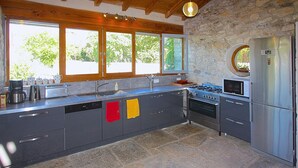 Une cuisine moderne avec un mur en pierre, un plafond en bois et de grandes fenêtres.