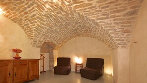Une pièce chaleureuse avec un plafond en pierre, des meubles en bois et deux chaises.