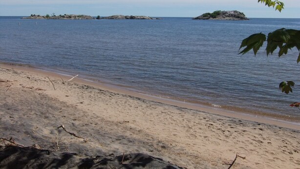 Una playa con agua cristalina, una orilla arenosa y islas a lo lejos.