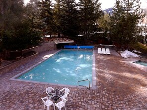Relax by the serene pool surrounded by lush greenery and a brick patio.
