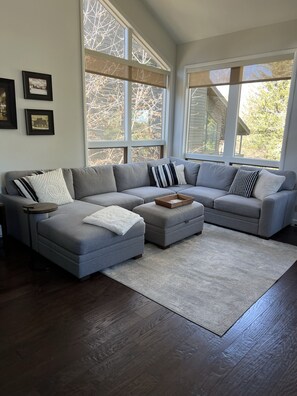 Relax in this inviting living space with a large sofa, framed artwork, and a view of the outdoors.