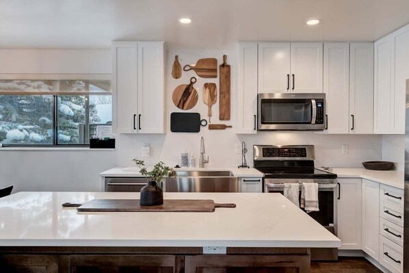 Enjoy cooking in this well-equipped kitchen with a large island, microwave, oven, and sink.