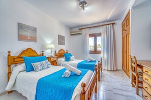 A hotel room with two beds, a wooden dresser, and a window with curtains.