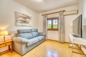 A living room with a sofa, a television, a lamp, and a painting on the wall.