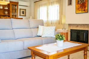 A living room with a sofa, a wooden coffee table, a fireplace, and a painting on the wall.