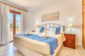 A hotel room with a bed, two bedside tables, a window with curtains, and a view of the outside.