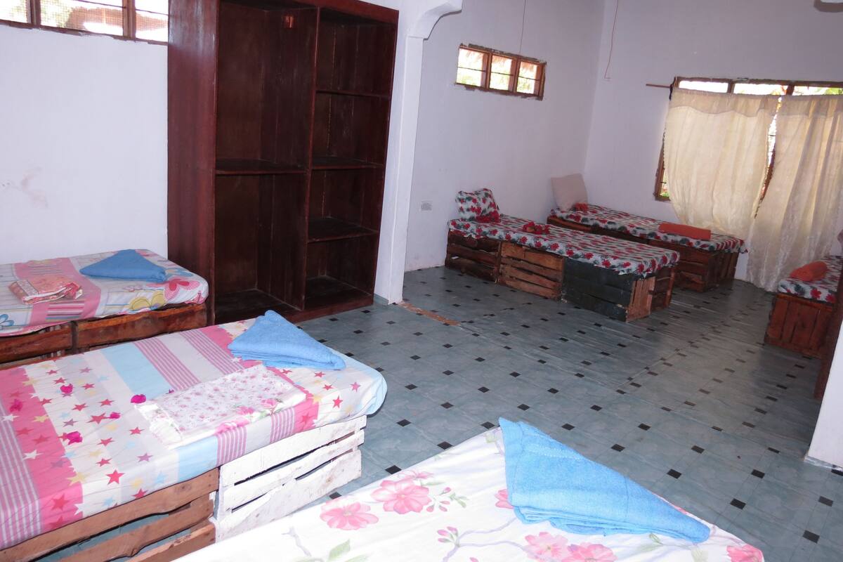 A room with two wooden beds, a wardrobe, and a small window.