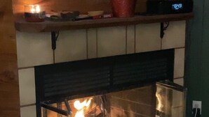 A fireplace with a visible fire, a clock, and a potted plant on the mantel. - Slopeside 2 Bedroom 2Bath-Great Value (Durango)