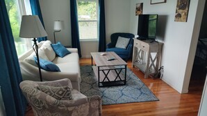 A living room with a sofa, armchair, coffee table, TV, and a cabinet.