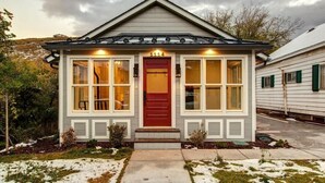 A small, single-story house with a red door, white trim, and a number '1114' above the door.