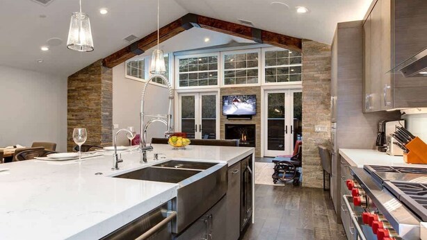 A modern kitchen with a large island, built-in appliances, and a stone accent wall.