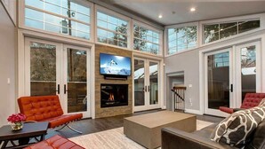 A spacious living room with a fireplace, large windows, and modern furniture.