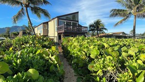 A modern house with a balcony, surrounded by lush greenery and palm trees. - BEACH FRONT ESTATE SANDY BEACH Heated Saline Pool 360 Views: Please Inquire (Waialua)