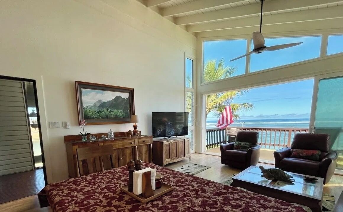 Un salon spacieux avec un grand lit, une télévision et un balcon offrant une vue sur l’océan.