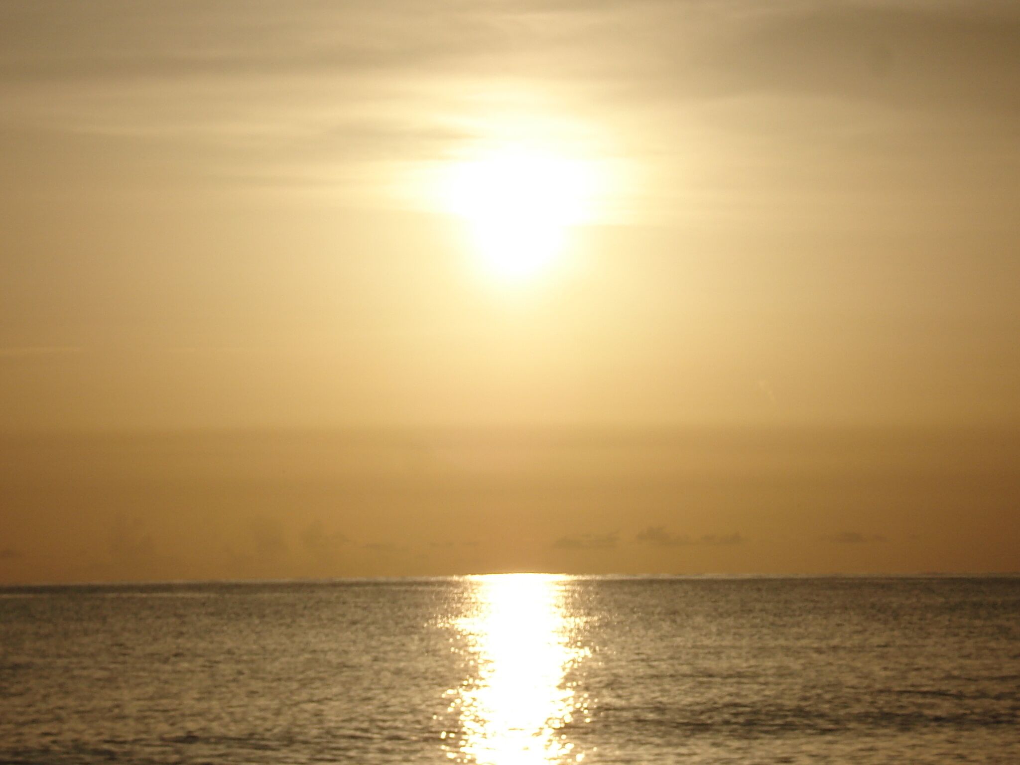 A sunset over the ocean with a clear sky.