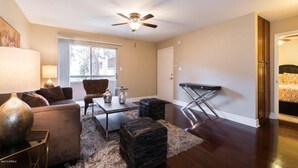 Un salon comprenant un canapé, une table basse, un pouf et un ventilateur de plafond.