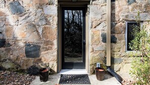 Vestíbulo de un edificio de piedra con puerta, buzón y pequeña ventana.