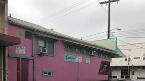 A pink building with a green roof and a sign that reads "Rainbow."