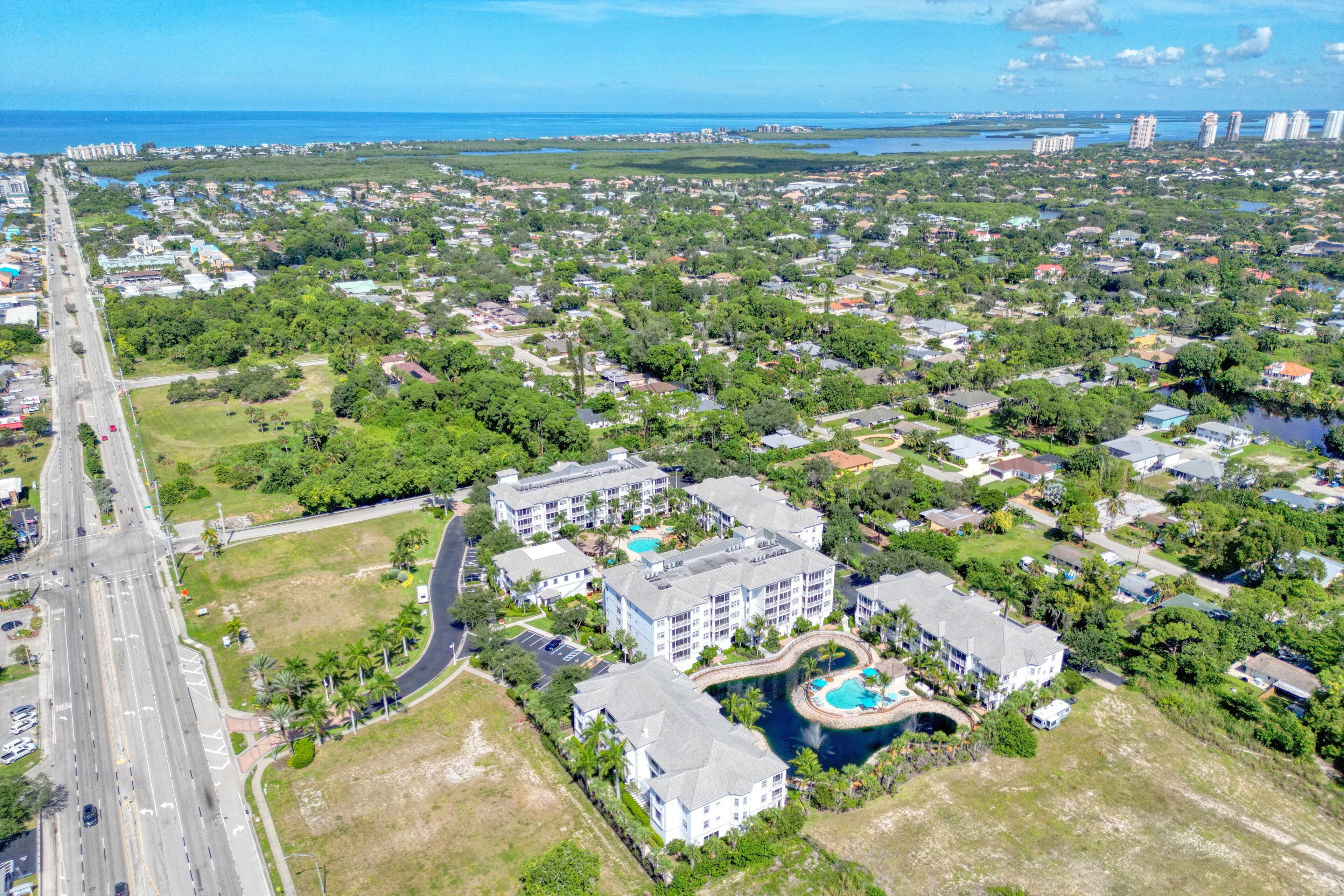 An aerial view of a coastal residential area with a large hotel featuring multiple buildings, a swimming pool, and a marina.