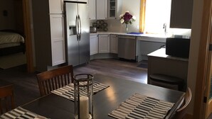 Eine kompakte Küche mit weißen Schränken, einem Kühlschrank, einem Geschirrspüler und einem Essbereich mit Tisch und Stühlen.