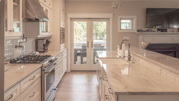 A modern kitchen with white cabinetry, a large island, and a built-in oven. - CORNER BEACH HOUSE - COTTAGE (Cape May)