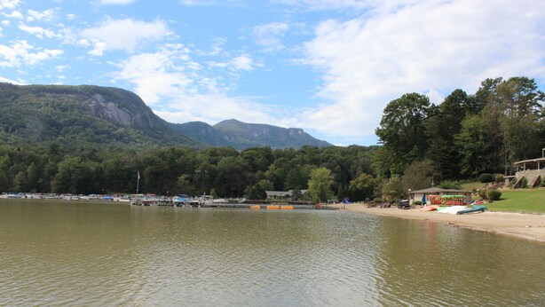 A lakeside view with boats, a dock, and a building with a sloped roof. - Honeycrisp Cottage at Lake Lure NC. We have recovered from Hurricane Helene! (Lake Lure)