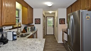 A kitchen with wooden cabinets, a stainless steel refrigerator, granite countertops, and a microwave. - Honeycrisp Cottage at Lake Lure NC. We have recovered from Hurricane Helene! (Lake Lure)