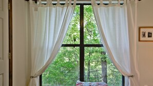 A bedroom with a large window, a quilt on the window sill, and a framed picture on the wall. - Honeycrisp Cottage at Lake Lure NC. We have recovered from Hurricane Helene! (Lake Lure)