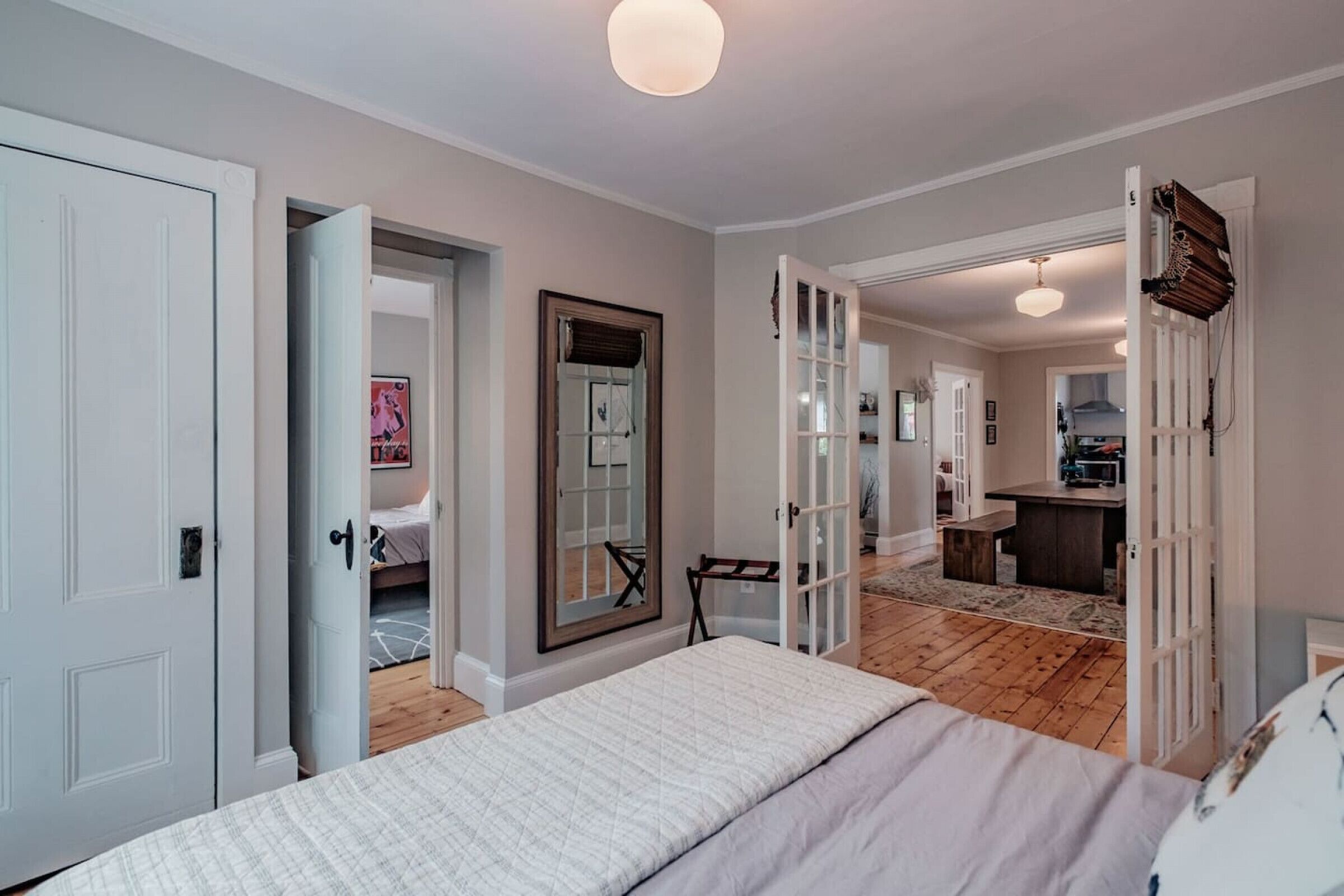 Un dormitorio con una cama, un espejo y una puerta que da a una zona de cocina.