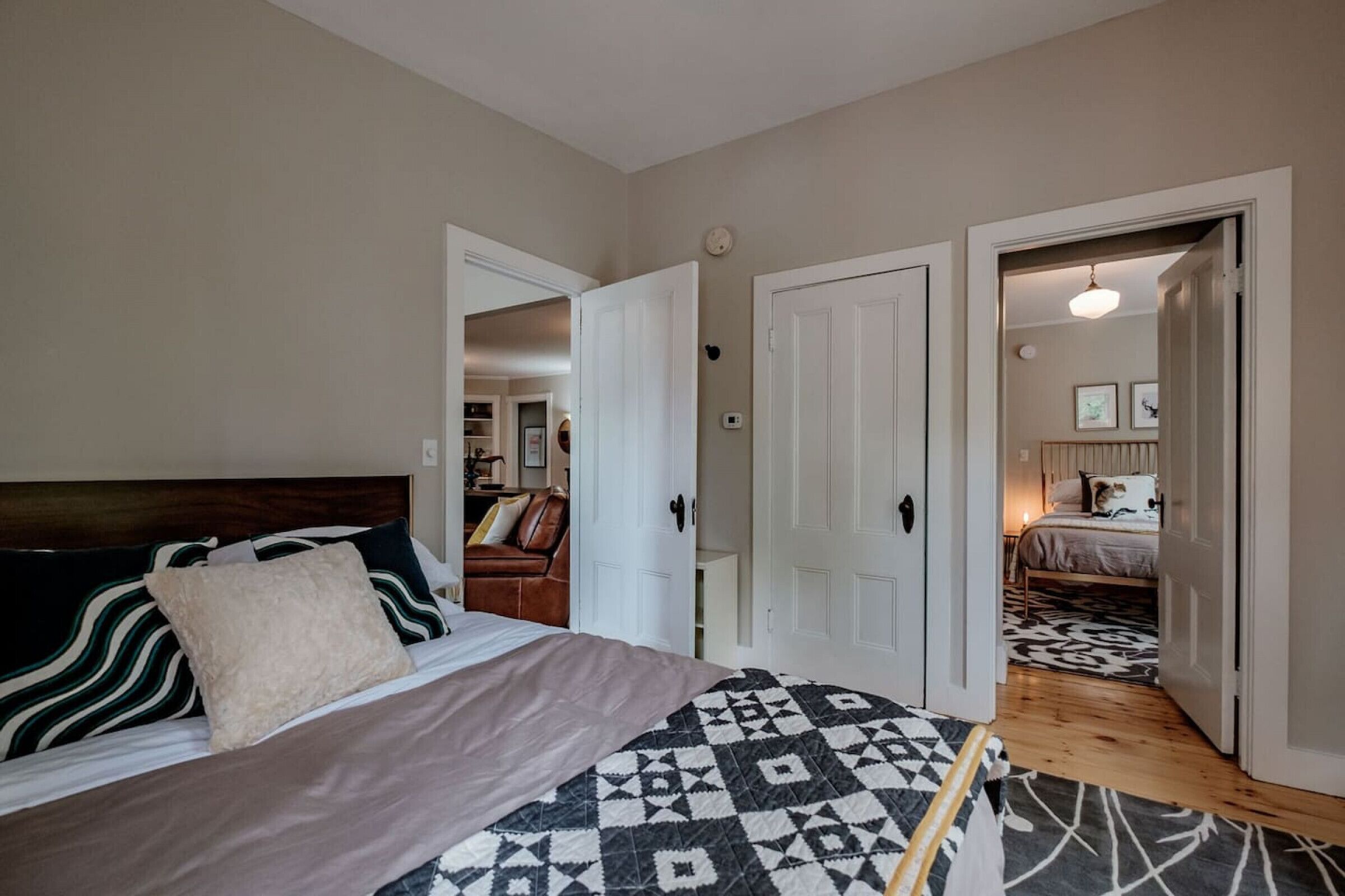 A bedroom with a bed, a door leading to another room, and a hallway.