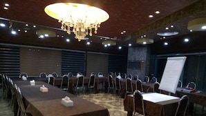 Un salón de conferencias con una larga mesa, sillas, una pizarra y una araña.