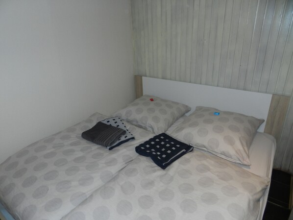 A bed with a patterned bedspread, two pillows, and a blanket. - Large family friendly apartment with terrace, (Ziegelroda)